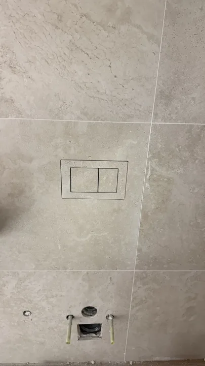 Buton shkarkimi i veshur me pllakë, gjatë montimit në murin e banios.